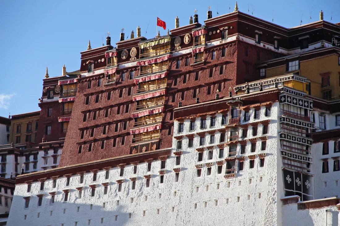 A close view of the Potala Palace's layered white walls, red buildings, and golden roofs