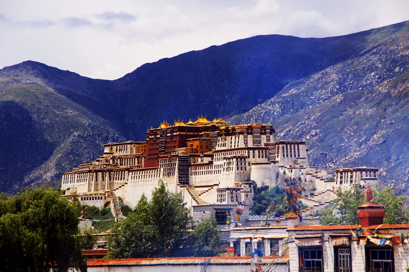 The white and ochre walls of the Potala Palace beneath the mountains of Lhasa, Tibet